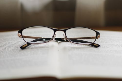 Free Close-up of reading glasses on an open book, symbolizing study and learning. Stock Photo
