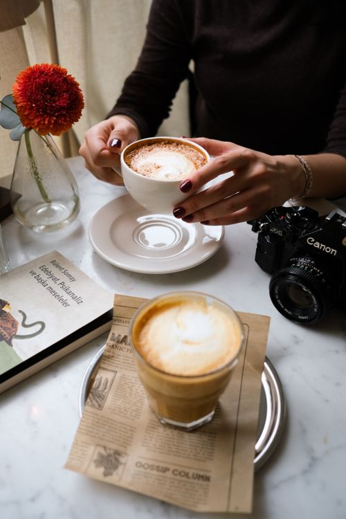 Free A relaxing coffee setup with latte, book, flower, and camera on a marble table. Stock Photo