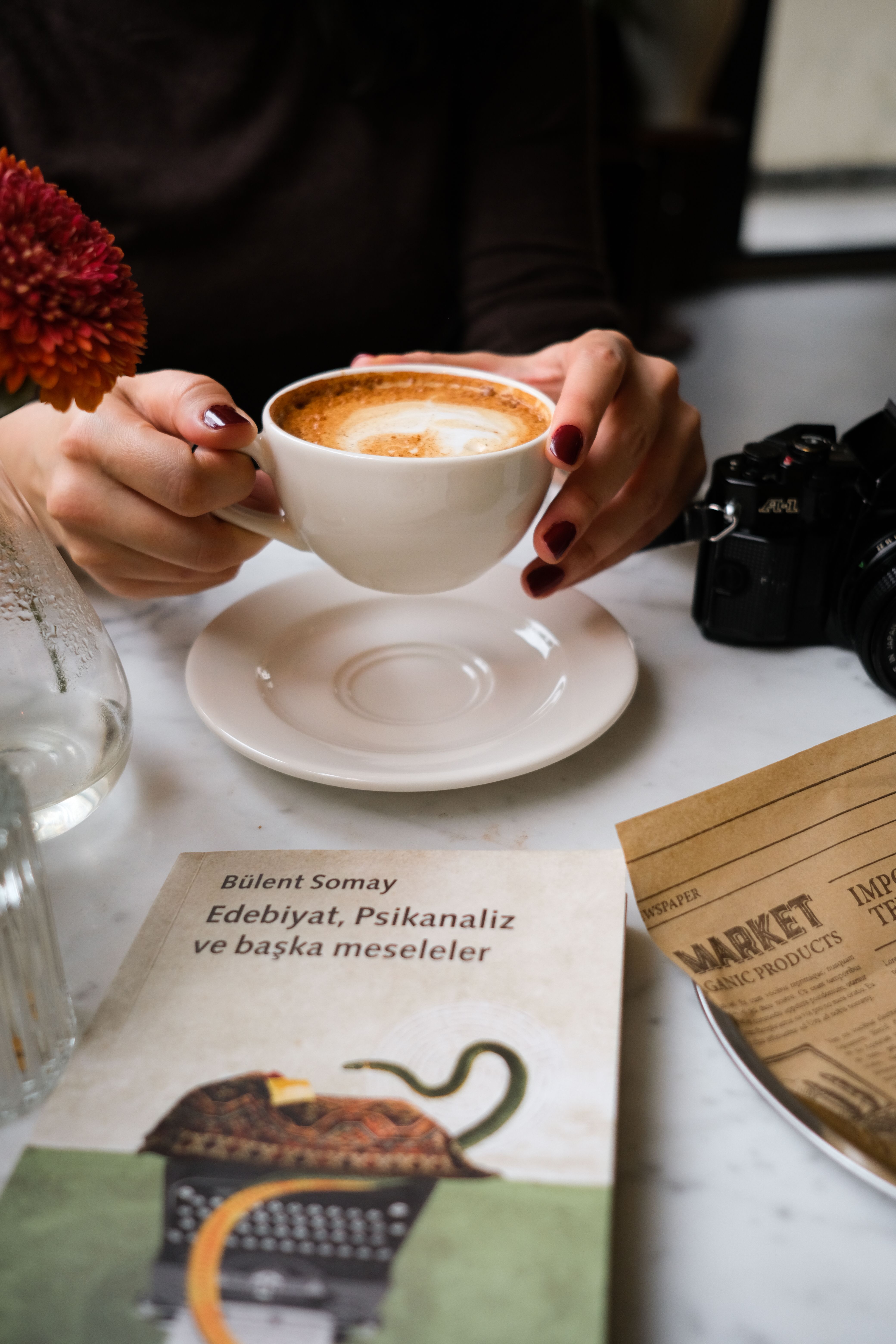 A warm cafe setting with coffee, book, and stylish atmosphere.