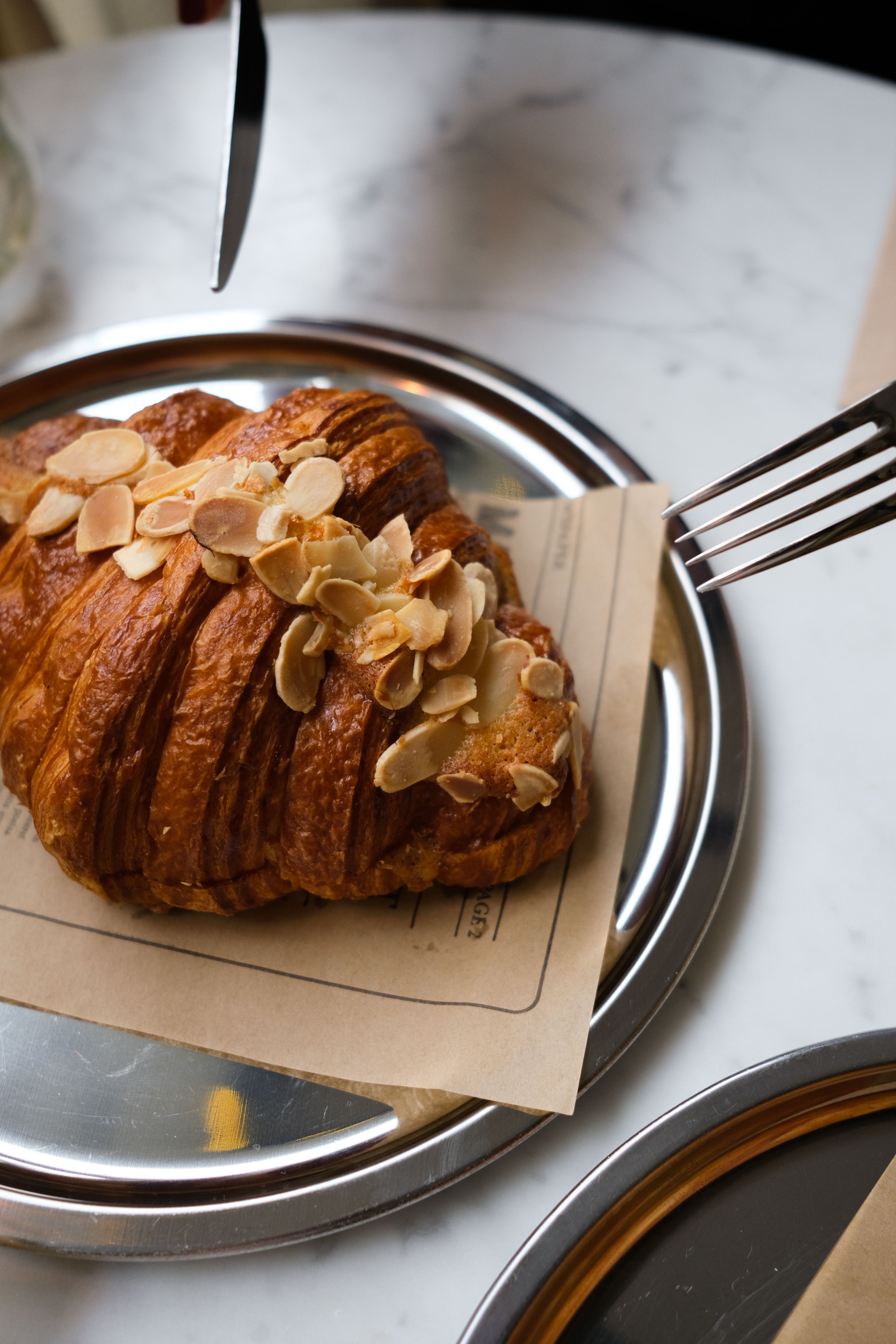 An almond croissant cut open on a ceramic plate