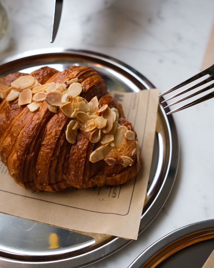 An almond croissant cut open on a ceramic plate
