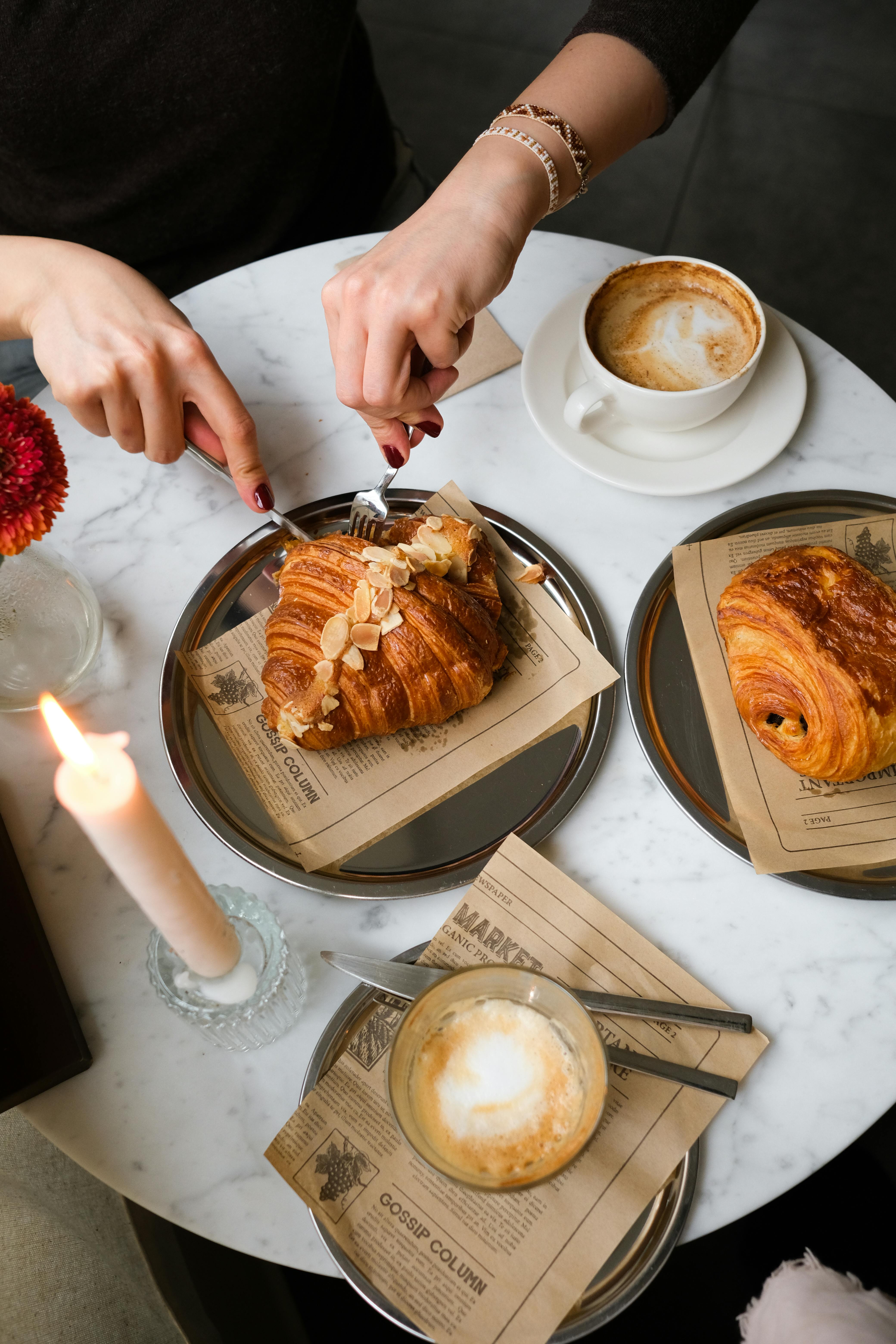 бесплатная Вид сверху на уютную обстановку для завтрака: круассаны и капучино на мраморном столе. Стоковое фото