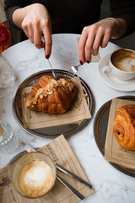 A delicious breakfast setting with almond croissants and coffee on a marble table.