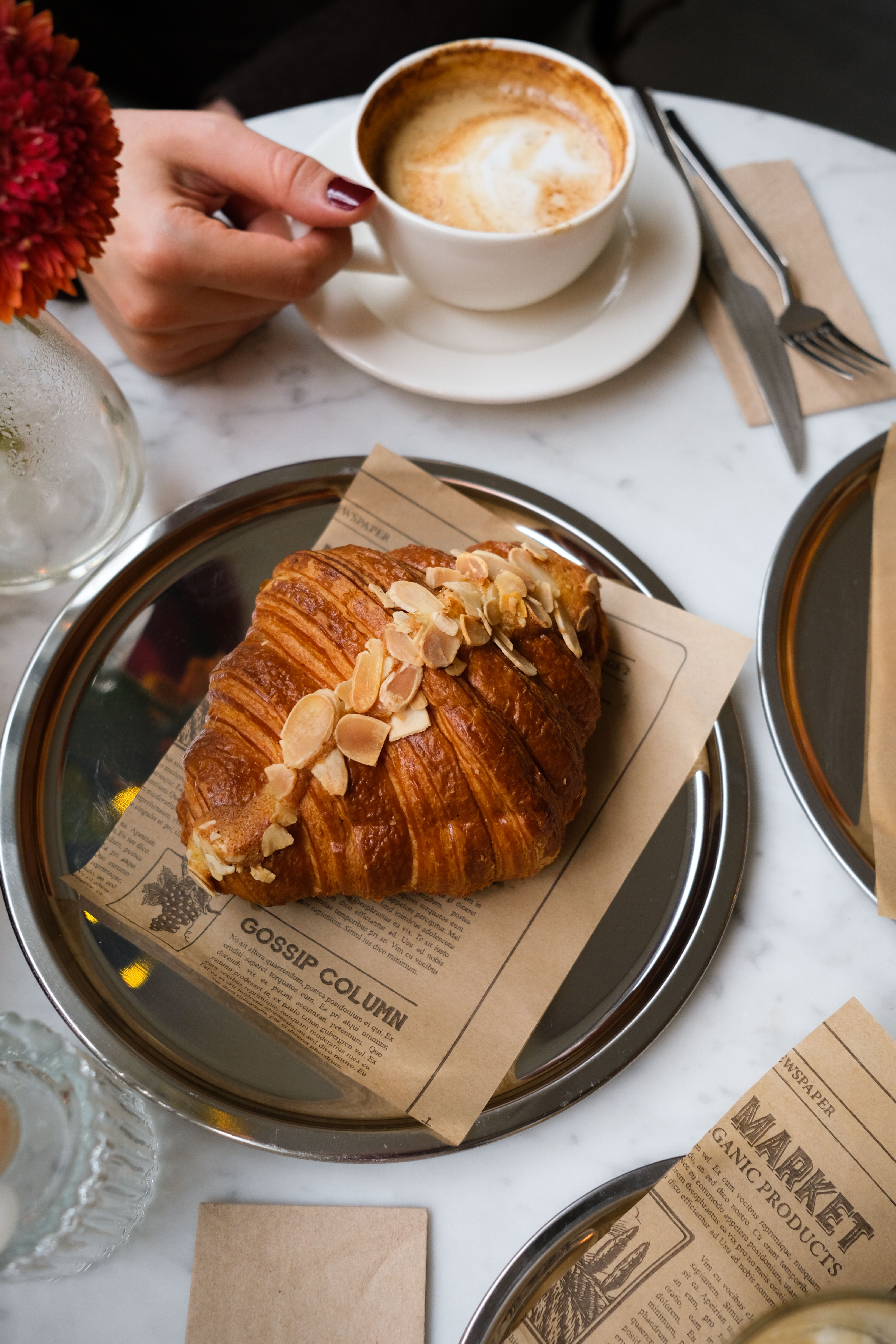 A tasty almond croissant with coffee on a table for a cozy cafe breakfast.