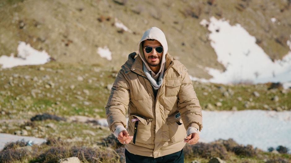 Man wearing winter gear hiking in a snowy mountainous landscape.