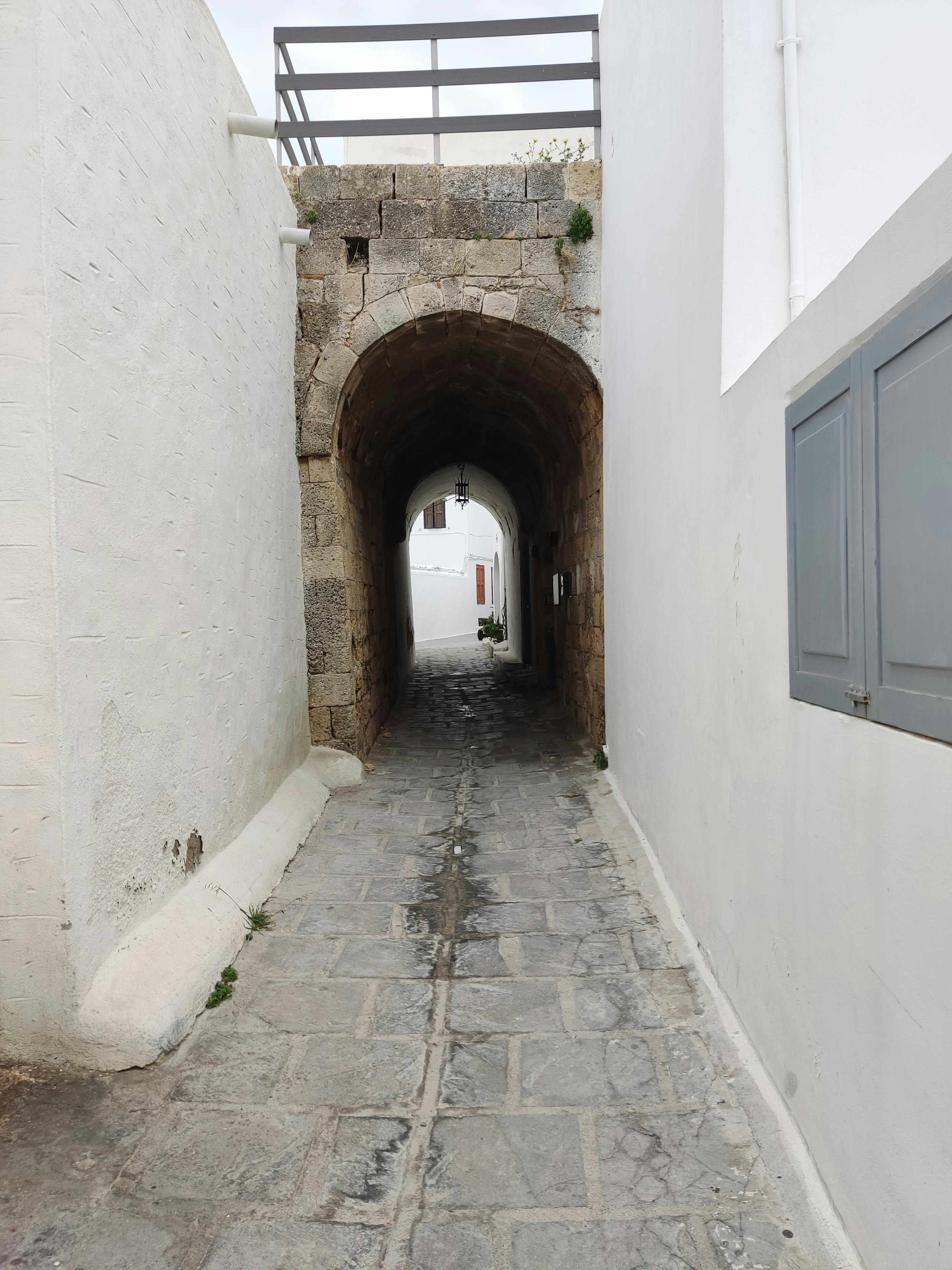 бесплатная Исследуйте традиционный каменный арочный проход в Линдосе, Греция, который хранит в себе очарование древности. Стоковое фото