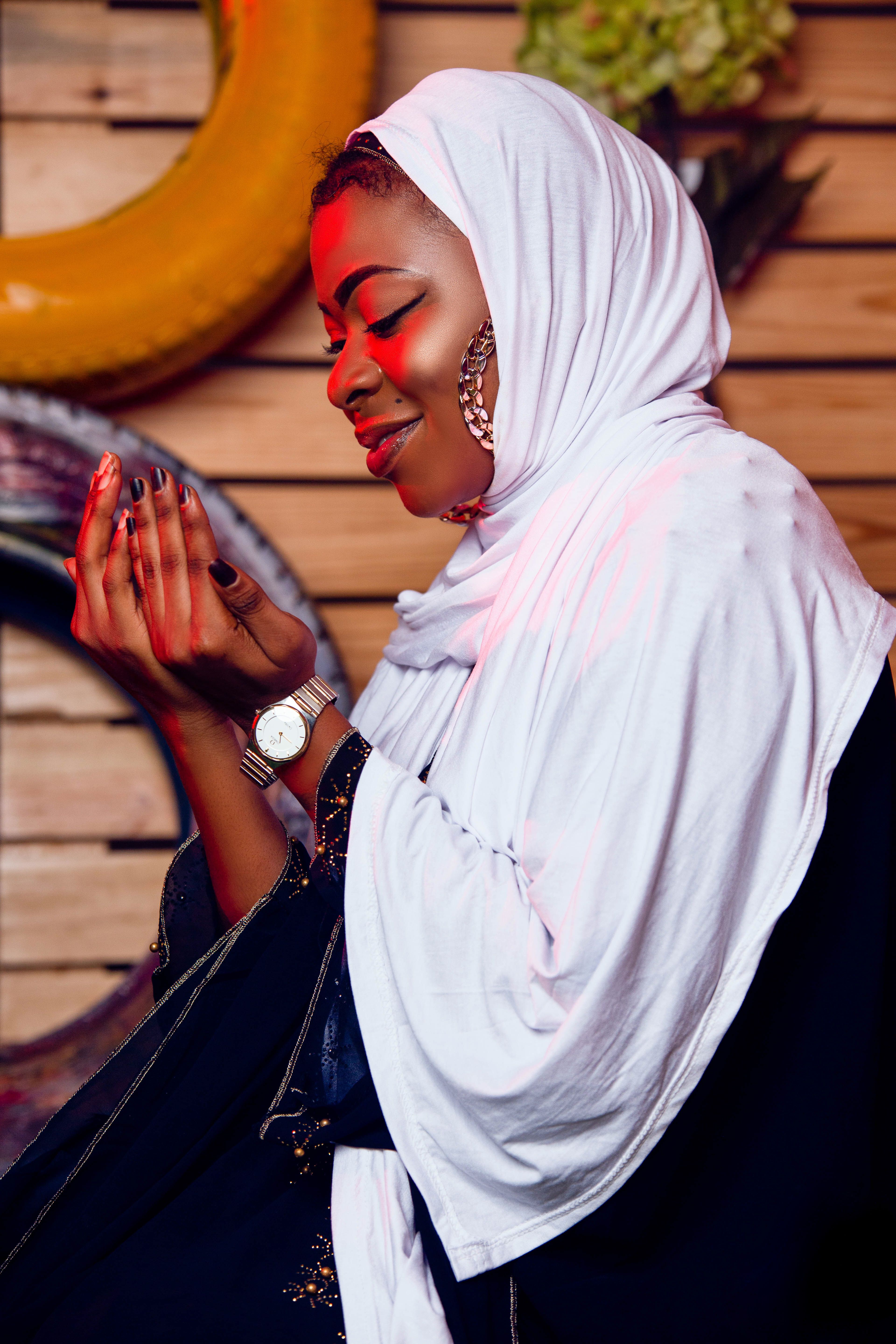 Confident woman in white hijab praying, exuding warmth and elegance.