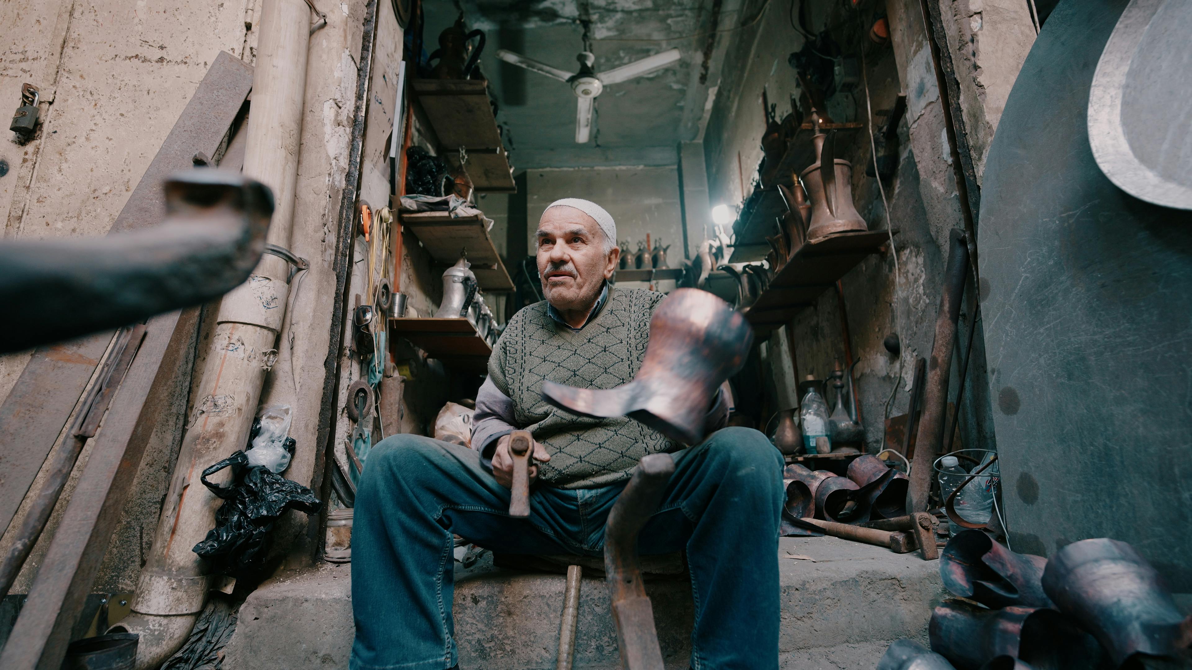 бесплатная Пожилой мастер работает над металлическими изделиями в традиционной мастерской. Стоковое фото