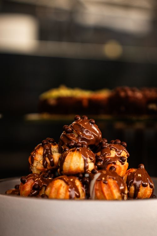 Free Decadent chocolate-drizzled profiteroles elegantly showcased in a dessert setting. Stock Photo