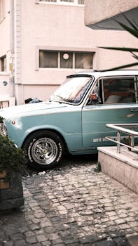 Vintage teal car on a cobblestone street, creating a nostalgic urban scene.