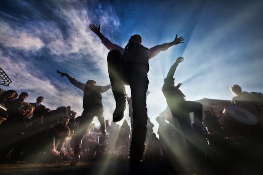 Energetic dance scene with silhouettes against a vibrant sky.