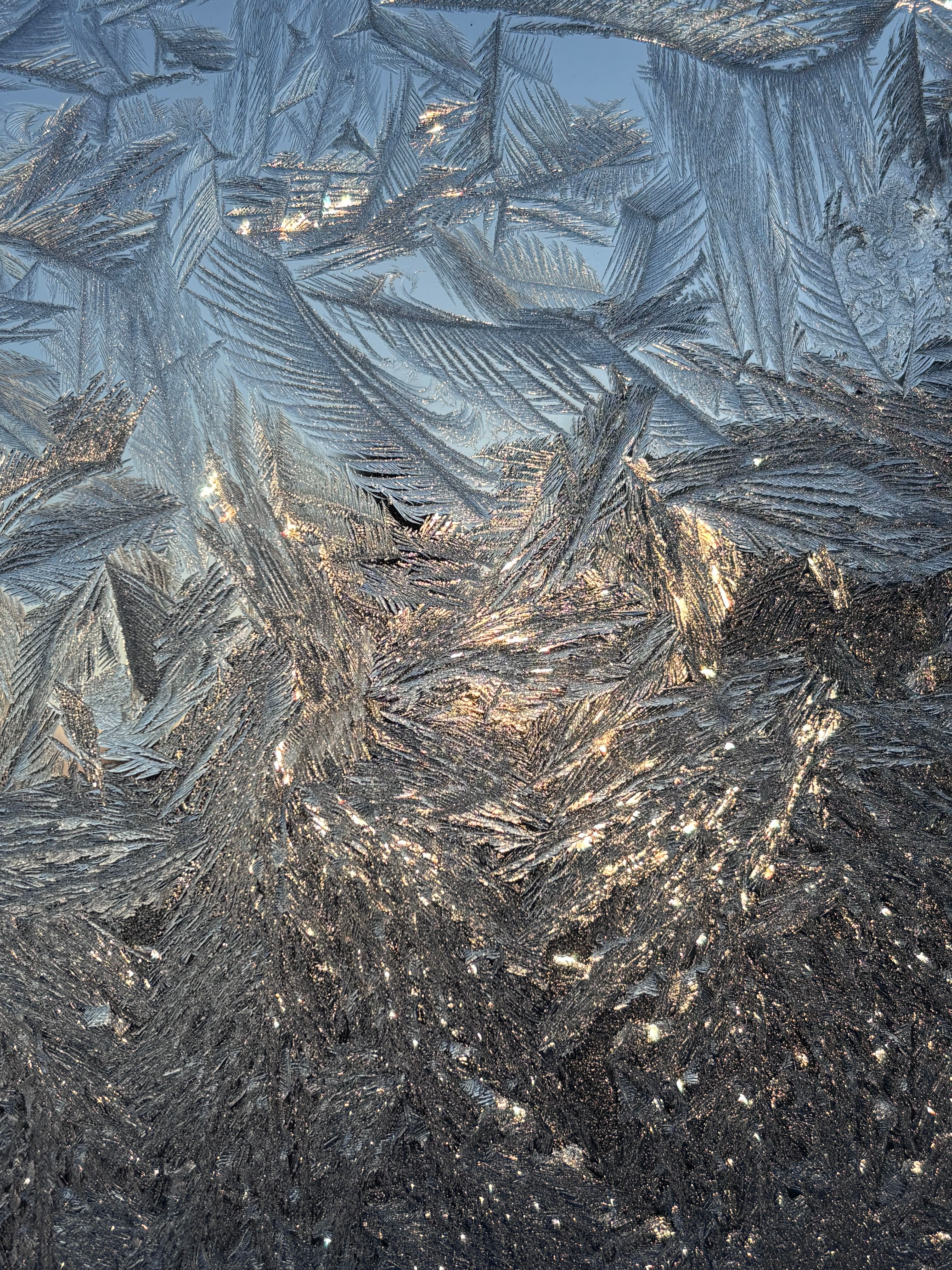 Detailed close-up of beautiful frost patterns on a window, illuminated by sunlight in Québec, Canada.