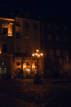 A picturesque European street scene at night with historic architecture and warm streetlights casting a soft glow.