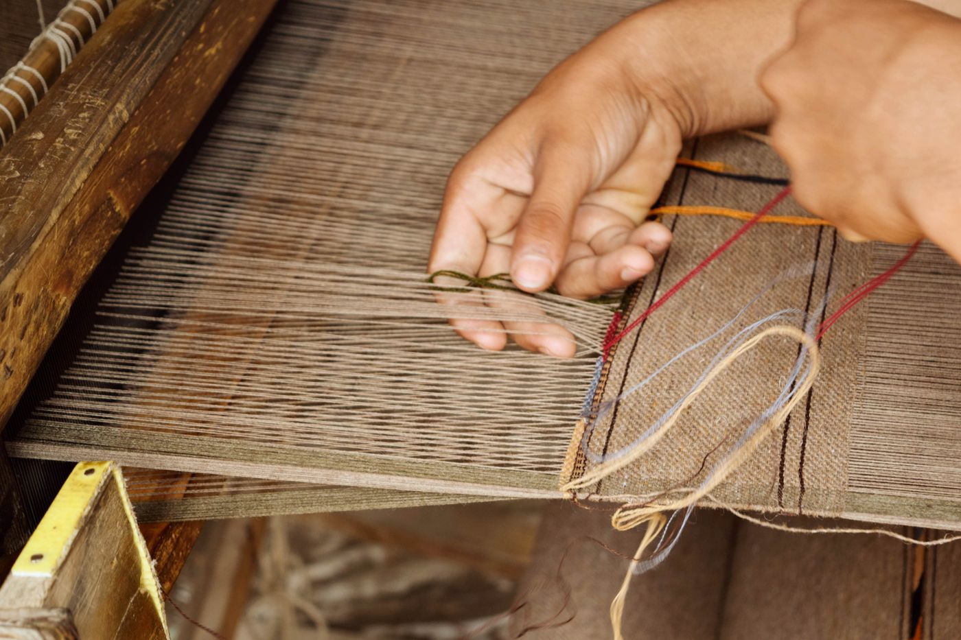 Artisan weaving fabric by hand on a loom