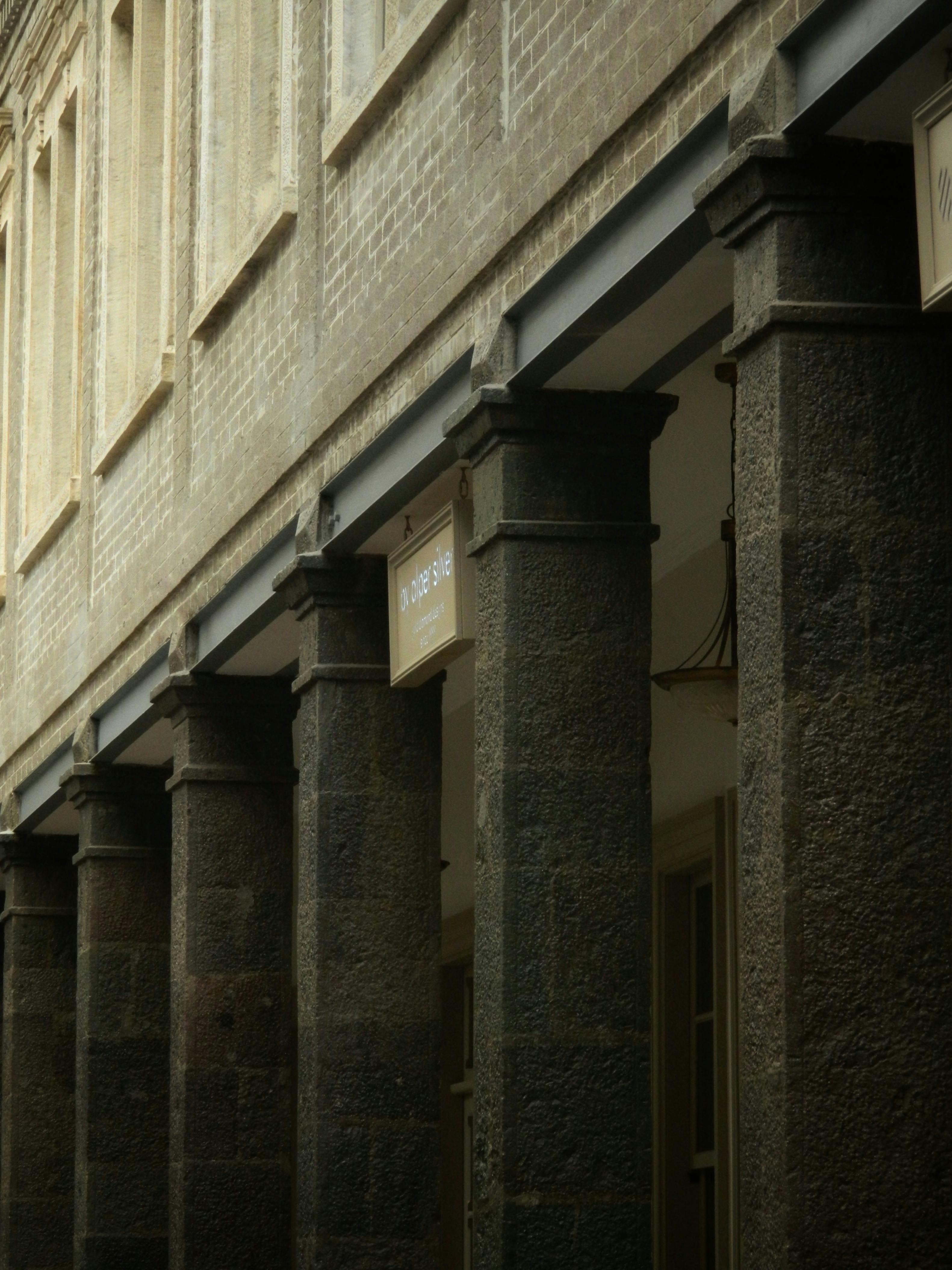 Gratis Nærbillede af historiske stensøjler, der understøtter en klassisk bygningsfacade. Lagerfoto