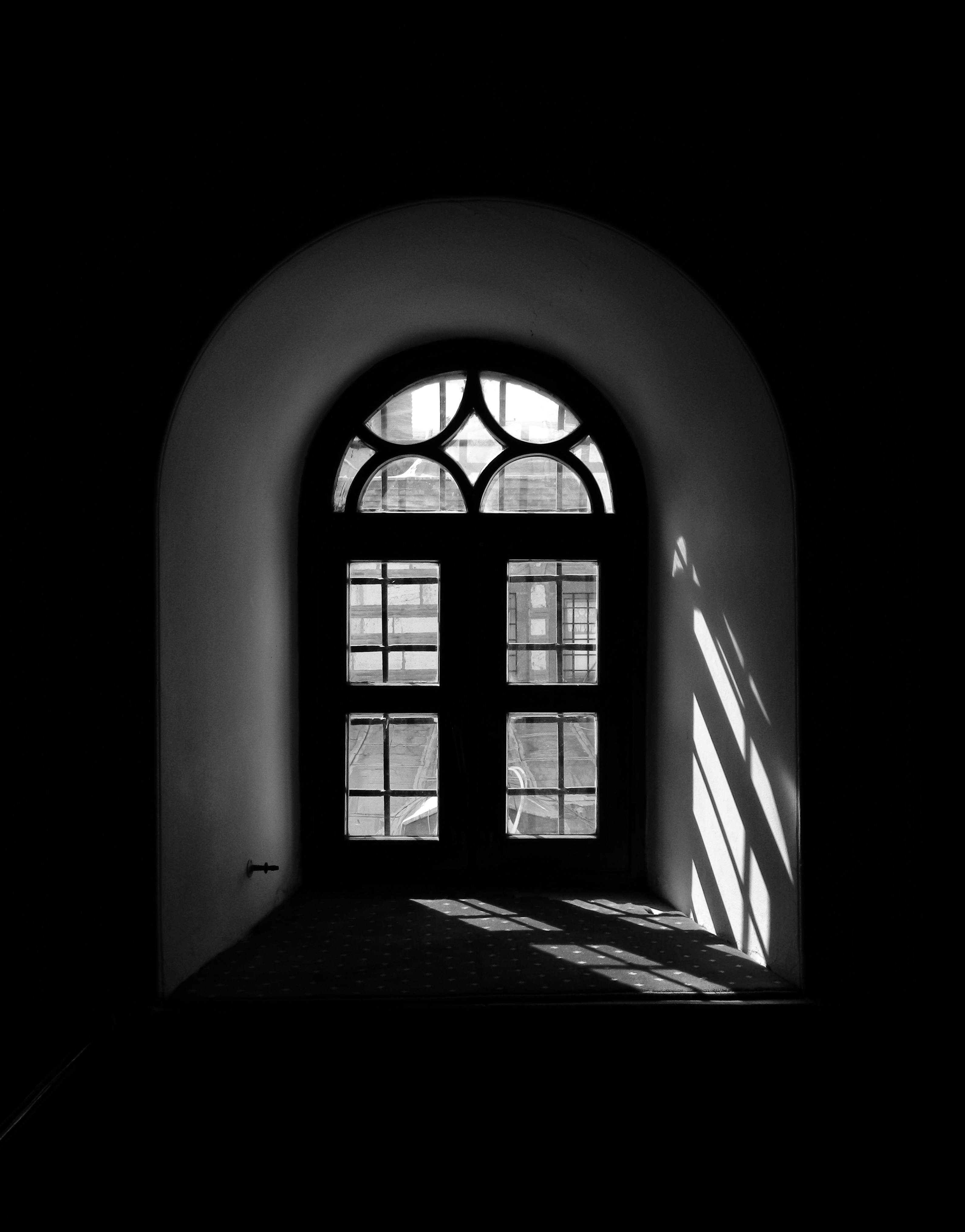 Gratis Fotografía en blanco y negro de una ventana con arco que proyecta sombras intrincadas en el suelo. Foto de stock
