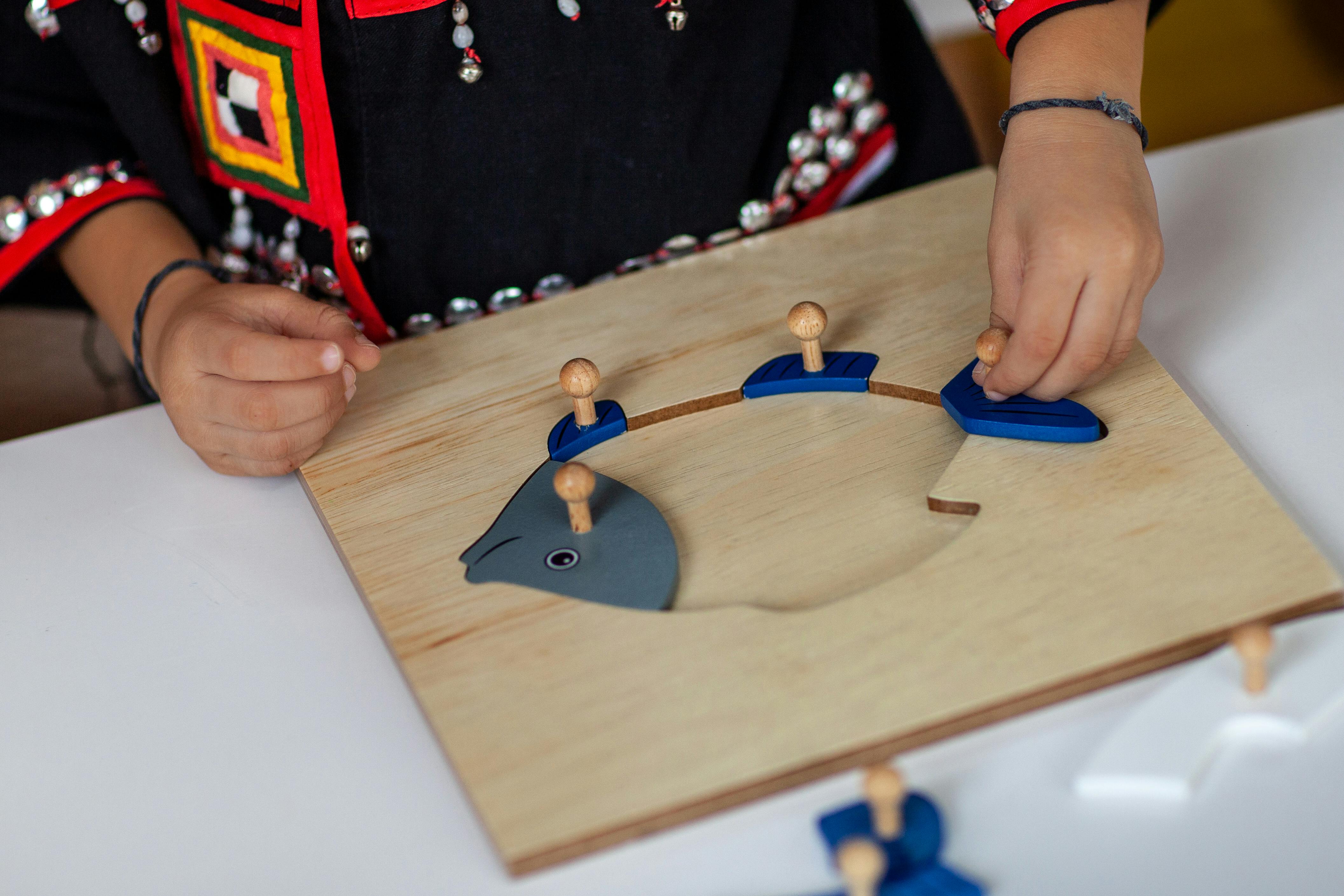 Child in traditional outfit assembling wooden fish puzzle indoors.