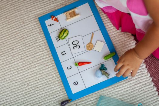 Child interacting with Montessori educational mat engaging in preschool learning activity. — photo by Ian Taylor