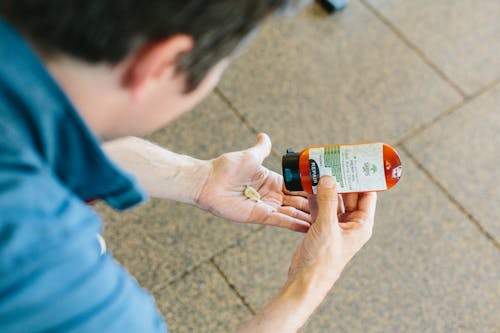 Person, Die Orange Und Weiß Beschriftete Flasche Hält