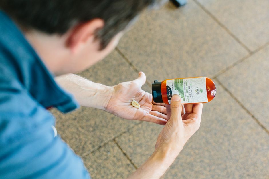 A person applying a CBD topical cream to their wrist. - Cat joint pain