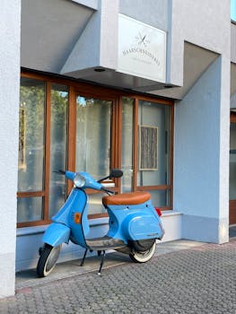 Stylish blue Vespa parked outside a modern hair salon facade, perfect for urban lifestyle themes.