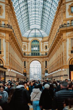 Elegant interior of Galleria Vittorio Emanuele II bustling with a diverse crowd in Milan, Italy.