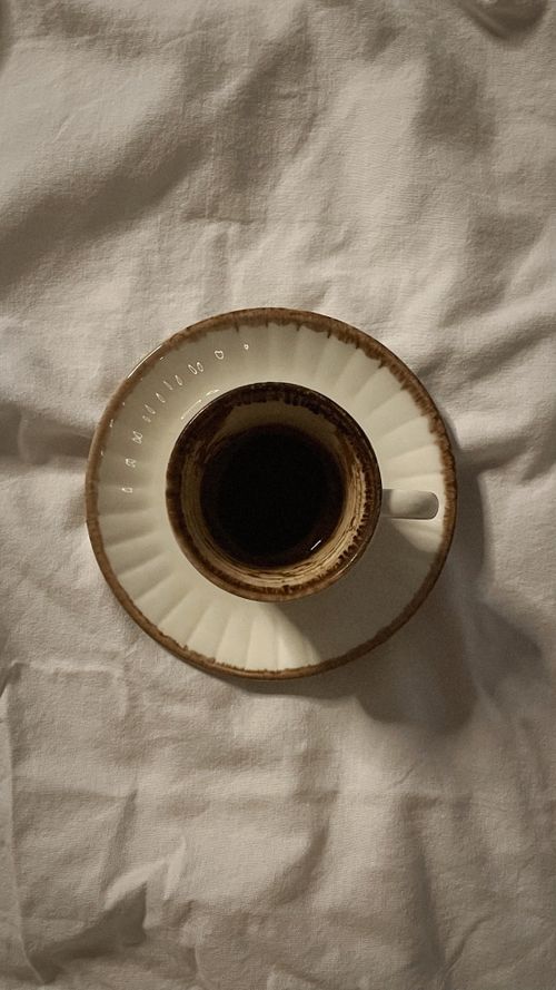 Free Overhead shot of a brown coffee cup resting on a white linen cloth. Stock Photo