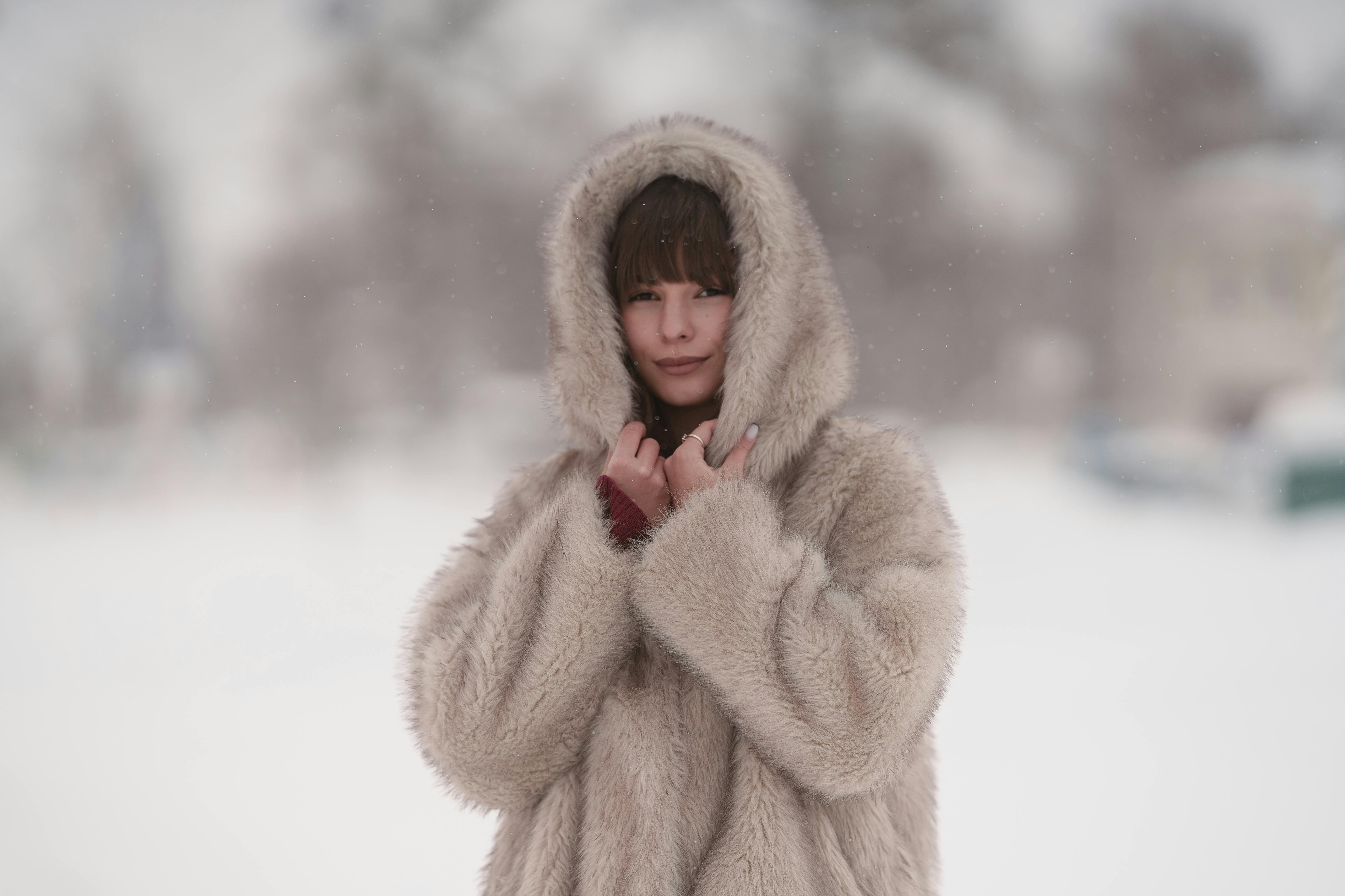 Free A woman in a cozy fur coat standing outdoors in a scenic snowy landscape. Stock Photo