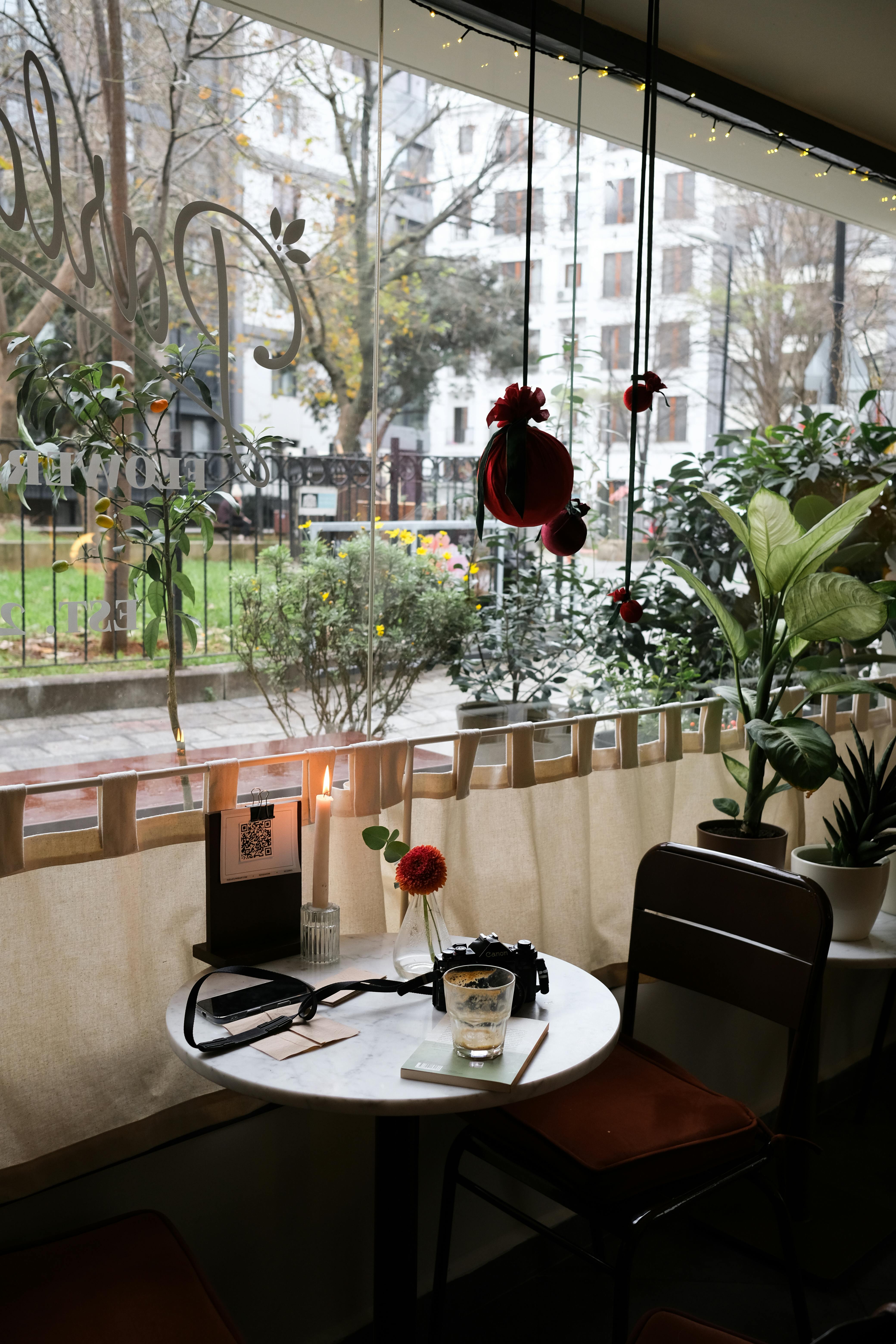 Free Inviting cafe interior with a charming window view, perfect for a cozy afternoon or atmospheric reading session. Stock Photo