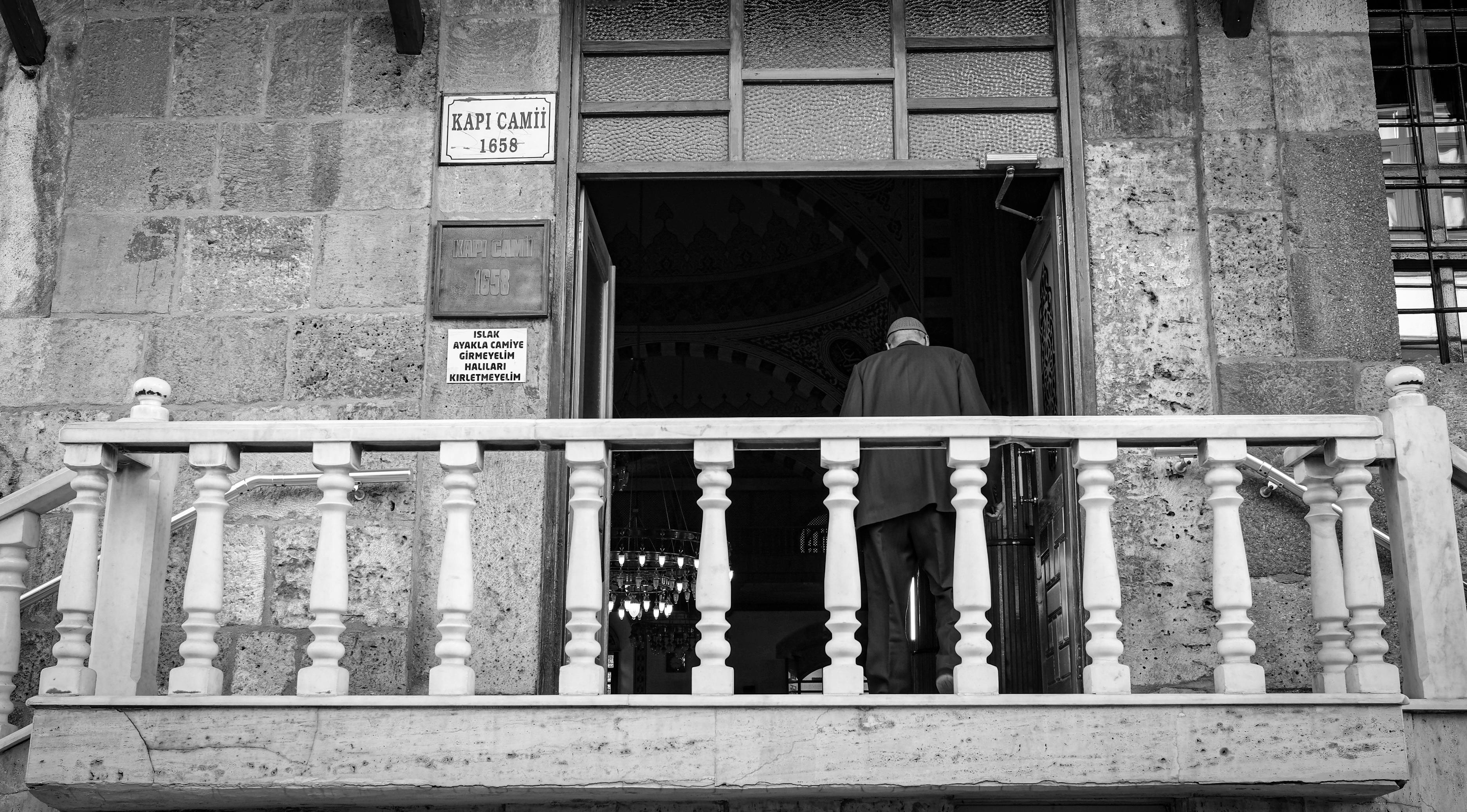 Gratis Foto in bianco e nero di un uomo anziano che entra in una moschea in Turchia. Foto a disposizione