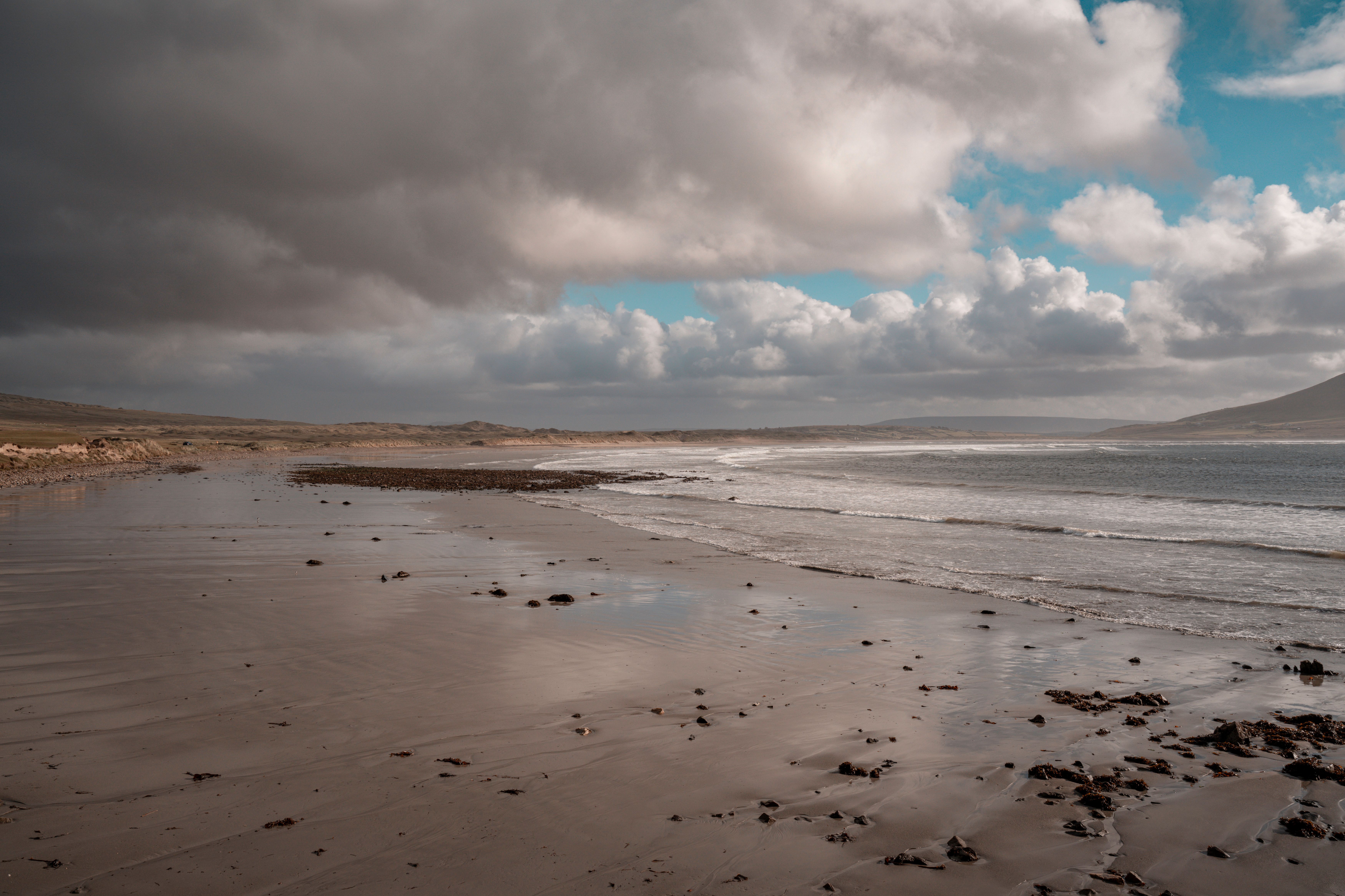 Capture of a serene Irish beach under dramatic clouds, offering a blend of tranquility and nature's raw beauty.