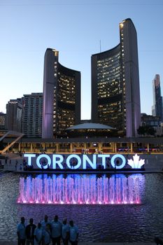 Toronto City Hall and illuminated fountain at twilight showcasing urban beauty.