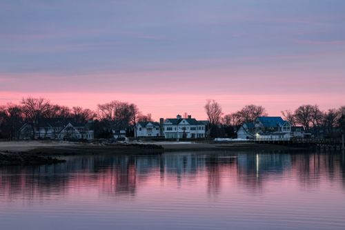 Free Charming waterfront homes reflected in a serene lake under a pink and blue twilight sky. Stock Photo