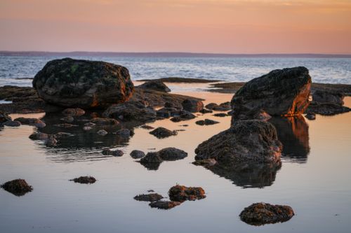 Free Peaceful coastal scene with rocks and reflective water at sunset. Stock Photo