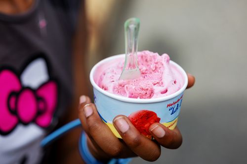 Free Hand holding pink ice cream in a cup with a spoon. Perfect for dessert-themed photography. Stock Photo