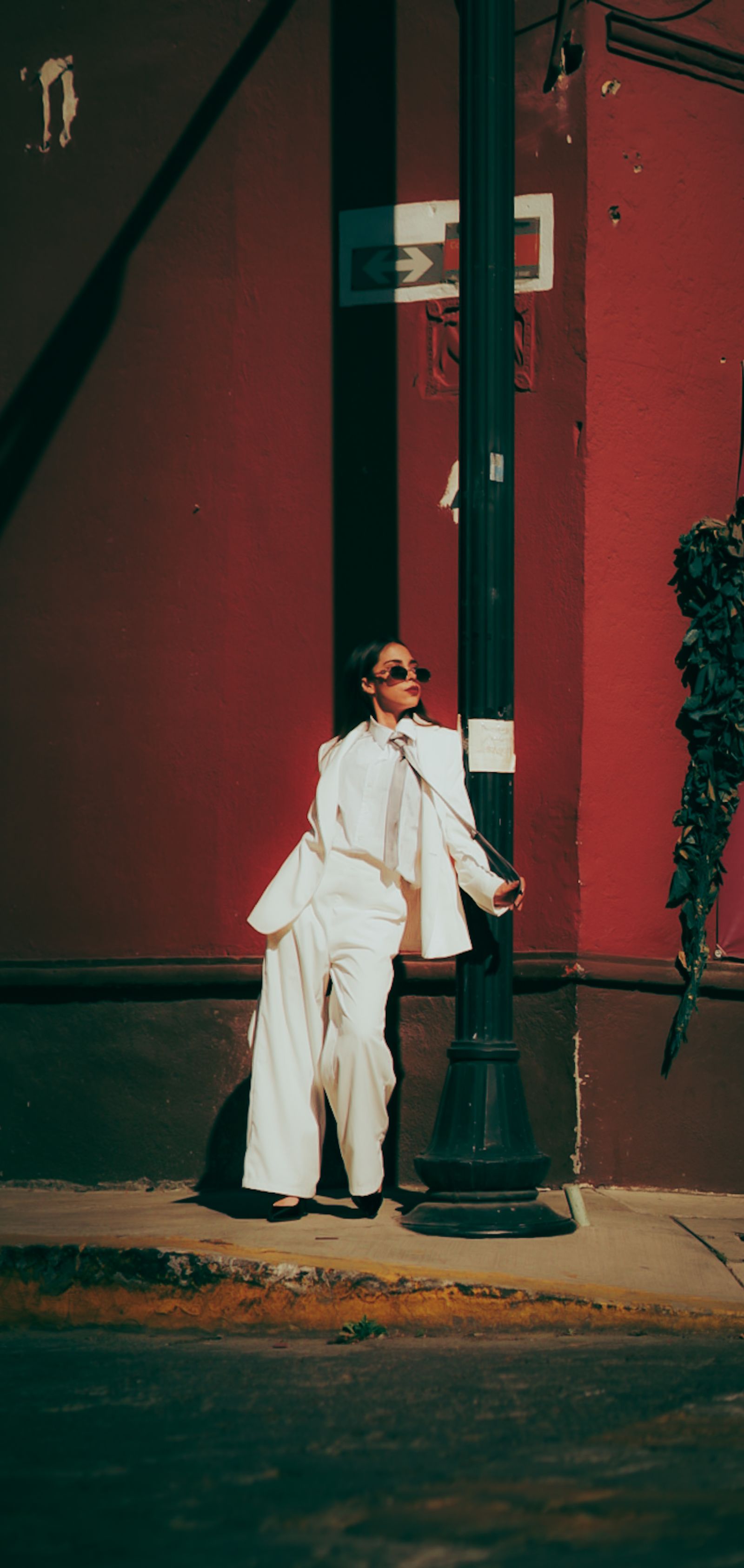 A stylish woman posing against an urban street wall in wide-leg trousers