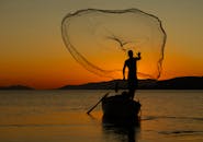 Silhouette of Fisherman Casting Net at Sunset