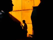 Silhouetted Figures Against Vibrant Orange Wall