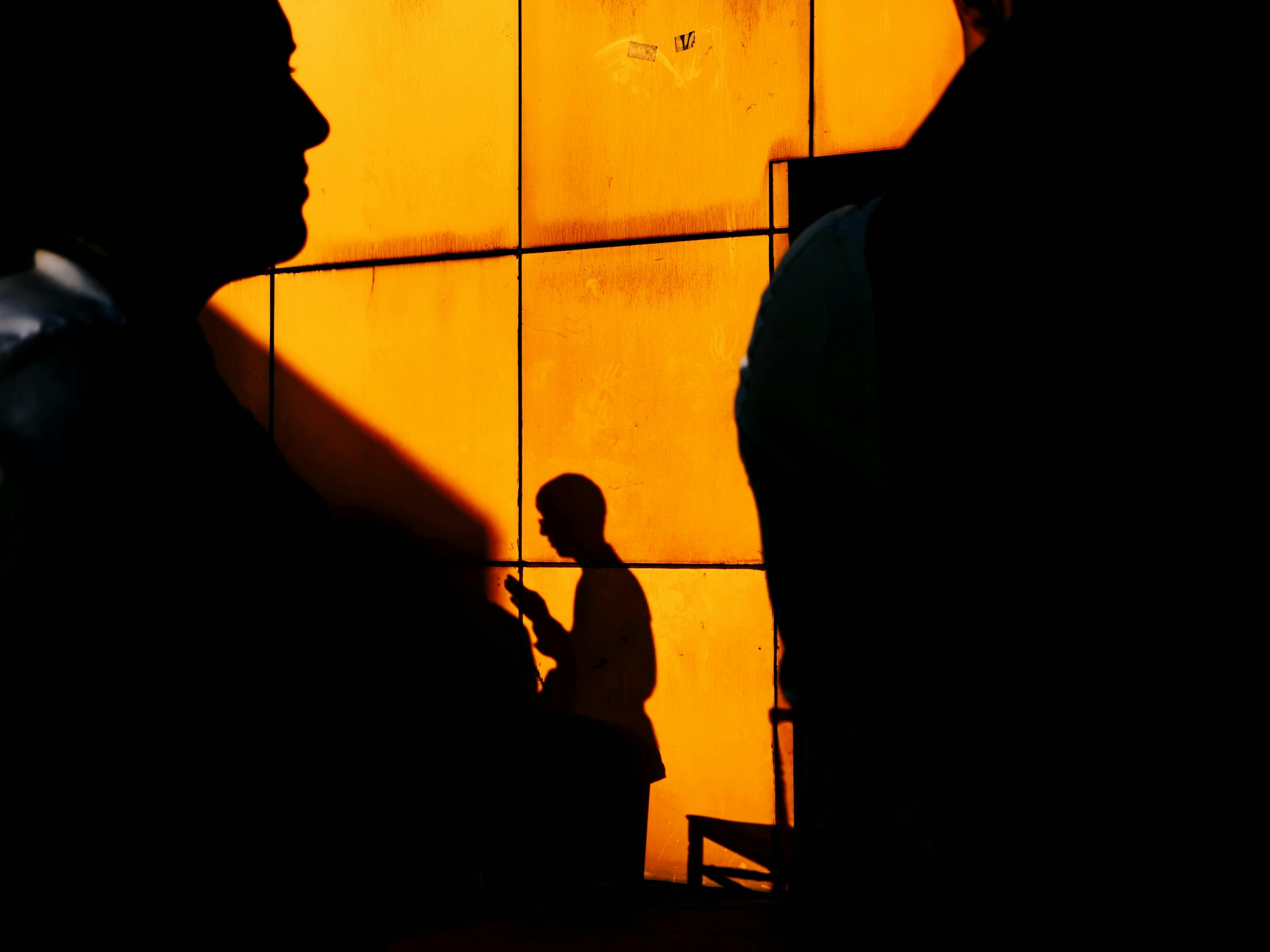 Free Artistic silhouettes cast on a vibrant orange wall in Istanbul, capturing urban life. Stock Photo