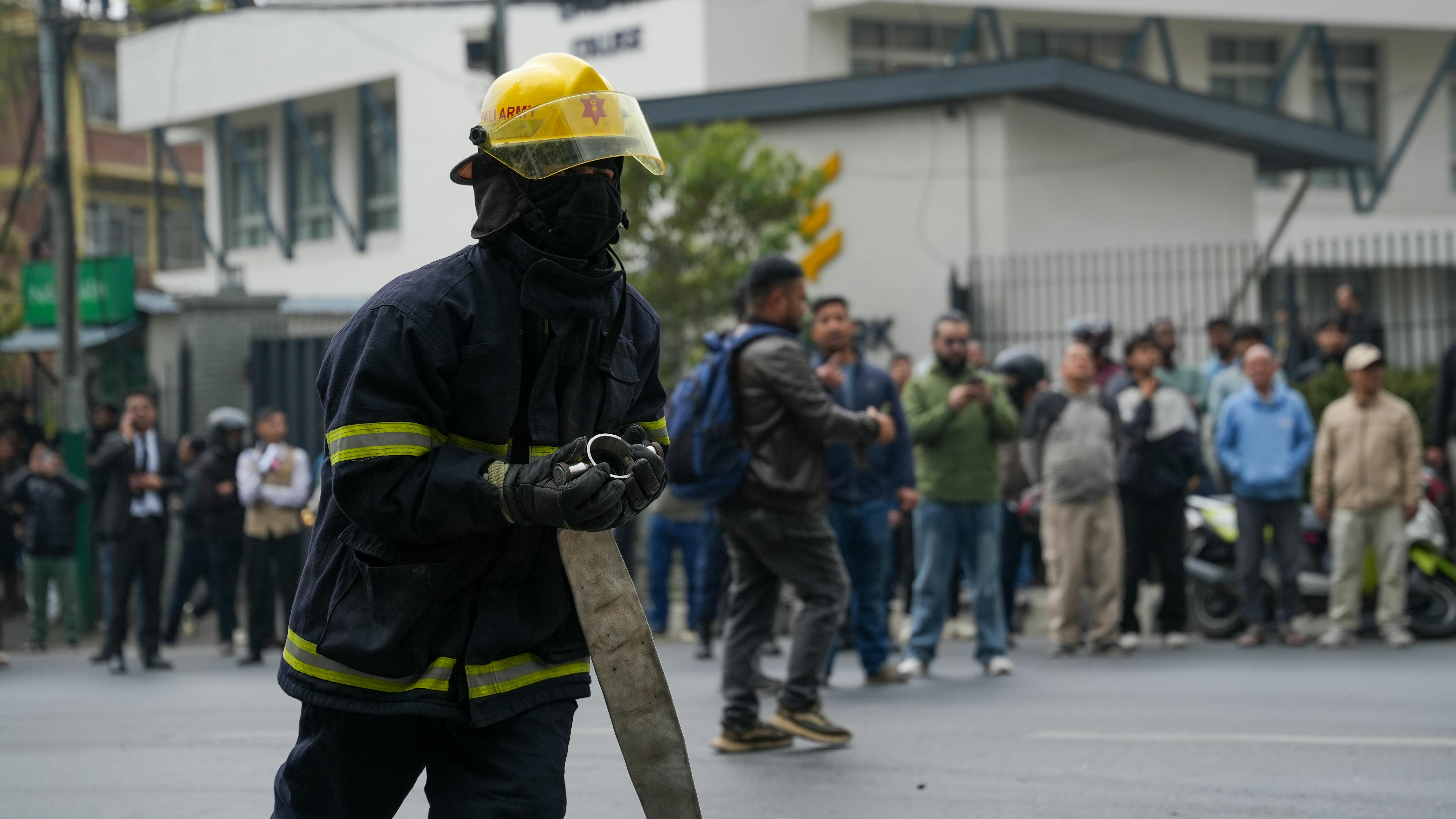 бесплатная Пожарный работает со шлангом во время чрезвычайной ситуации в городе, на заднем плане — толпа наблюдателей. Стоковое фото