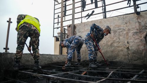 Free Rescue workers clean up debris on a rooftop in post-fire recovery effort, showcasing determination and teamwork. Stock Photo