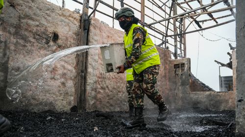 Free Firefighter in protective gear extinguishing flames in a burnt building. Emergency response in action. Stock Photo