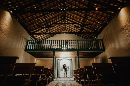 Bride and groom share a romantic kiss inside a rustic chapel.