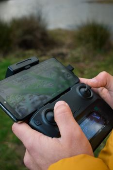 Close-up of hands operating a drone controller near a riverbank in Istanbul.
