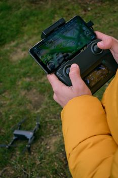 Close-up of hands operating a drone via smartphone outdoors.