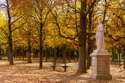 Elegant statue amidst autumn foliage in a Parisian park, captivating the essence of fall.