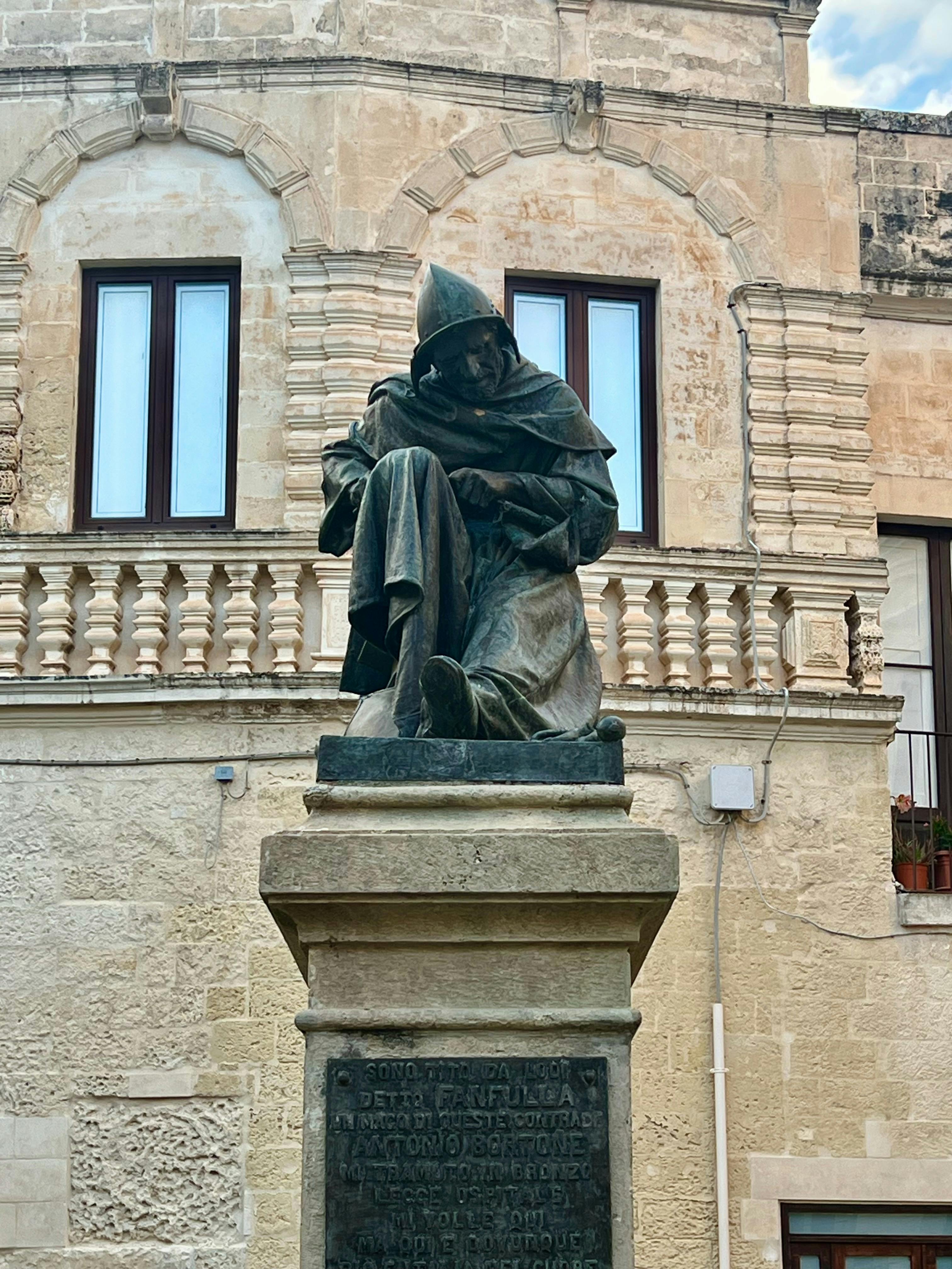 無料 イタリアのサルヴェにある歴史的建築物に立つ、フードをかぶった修道士の像。 写真素材