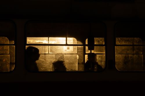 Free Passengers' silhouettes on a tram during sunset in Kyiv, casting a warm, moody glow through the windows. Stock Photo