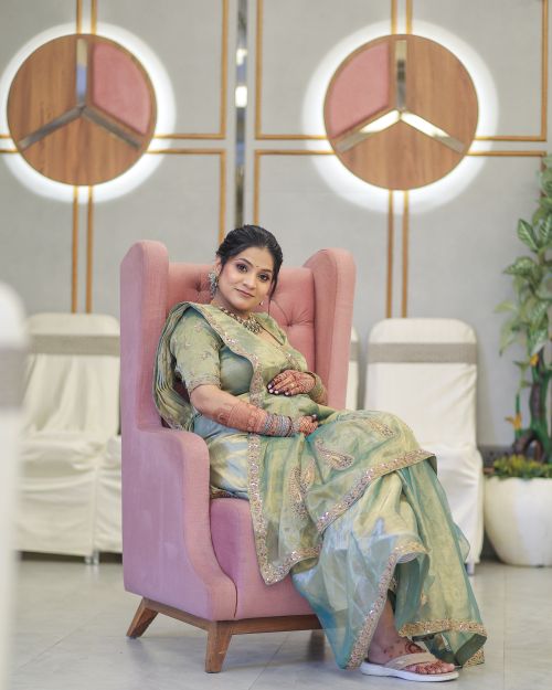 Free Pregnant woman in traditional attire seated in an elegant modern interior. Stock Photo