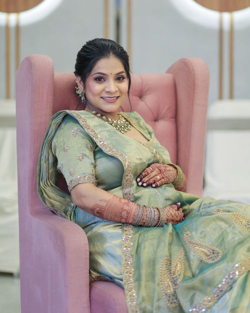 Free A beautiful maternity portrait showcasing a woman in traditional attire sitting gracefully in a modern chair. Stock Photo
